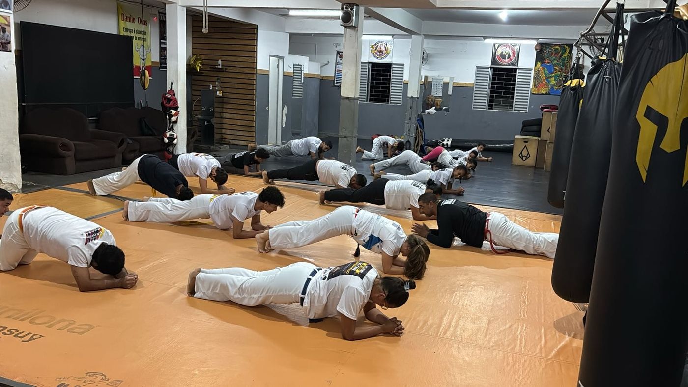 Alunos aquecendo no chão durante o treino no CT Furacão